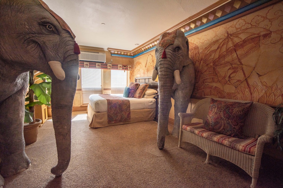 Une pièce comprenant une grande statue d’éléphant, un canapé et un mur orné de motifs.