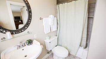 A bathroom with a white sink, toilet, and shower curtain.