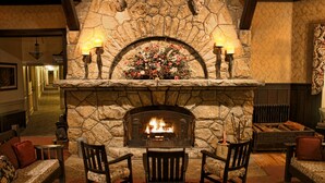 A stone fireplace with a fire, surrounded by two armchairs and a small table.
