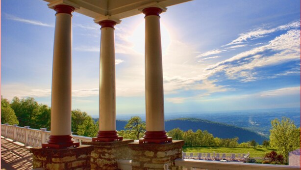 A covered porch with three columns and a view of the landscape.