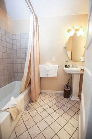 A bathroom with a bathtub, a sink, a mirror, and a shower curtain.