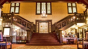 A grand staircase leading to a door, flanked by wooden railings and a chandelier.