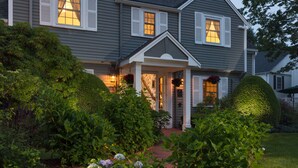 A two-story house with a covered porch, a well-maintained garden, and a driveway. - Old Harbor Inn (Chatham)