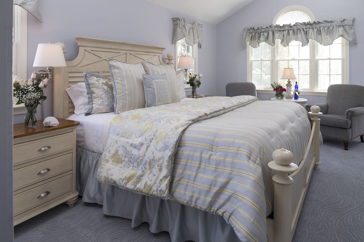 A bedroom with a large bed, bedside tables, a chair, and a window with curtains.