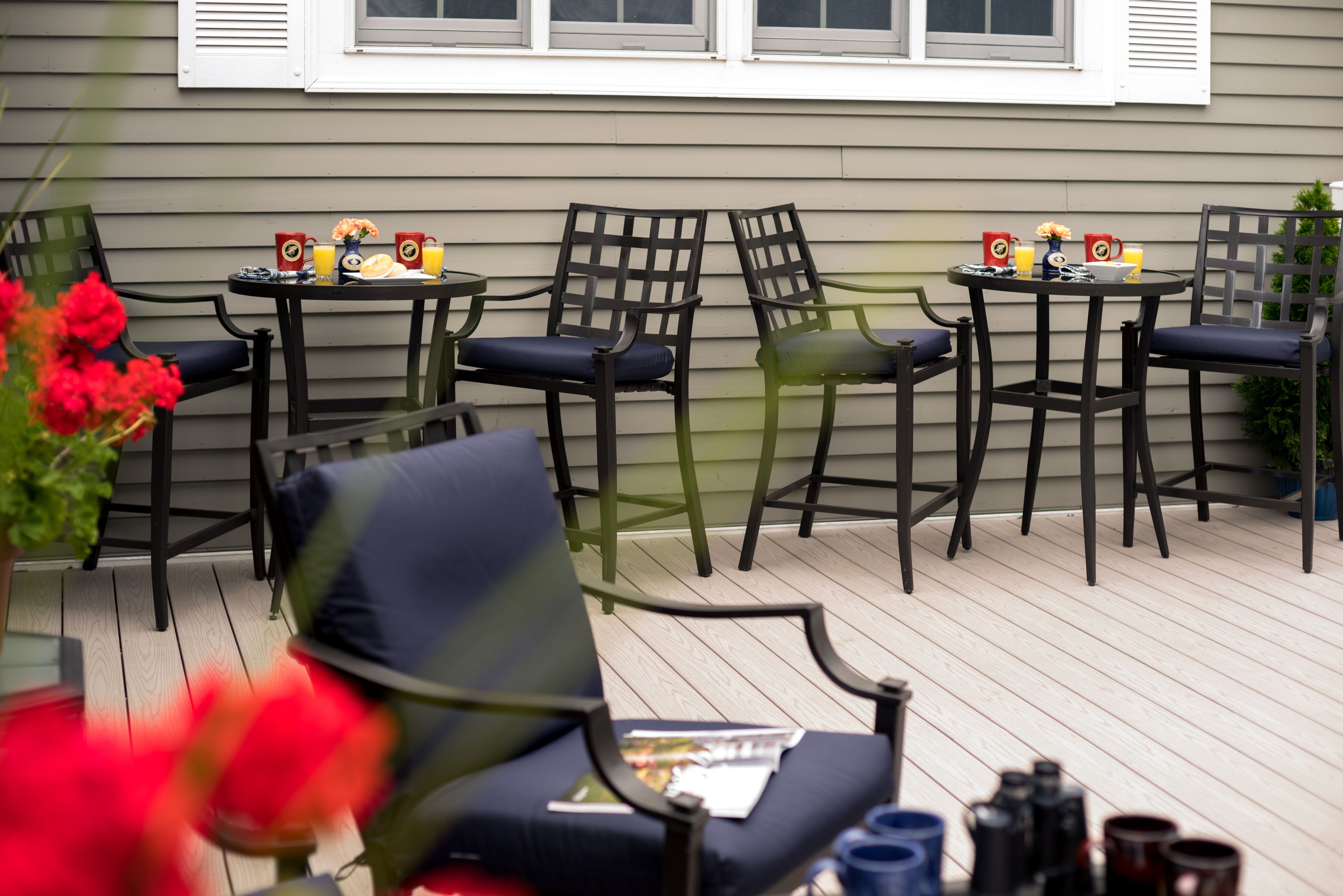 An outdoor patio with four tables and chairs, each set with a beverage and a bowl.