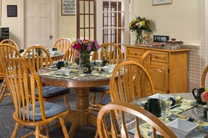 A dining room with a round table, wooden chairs, and a cabinet.