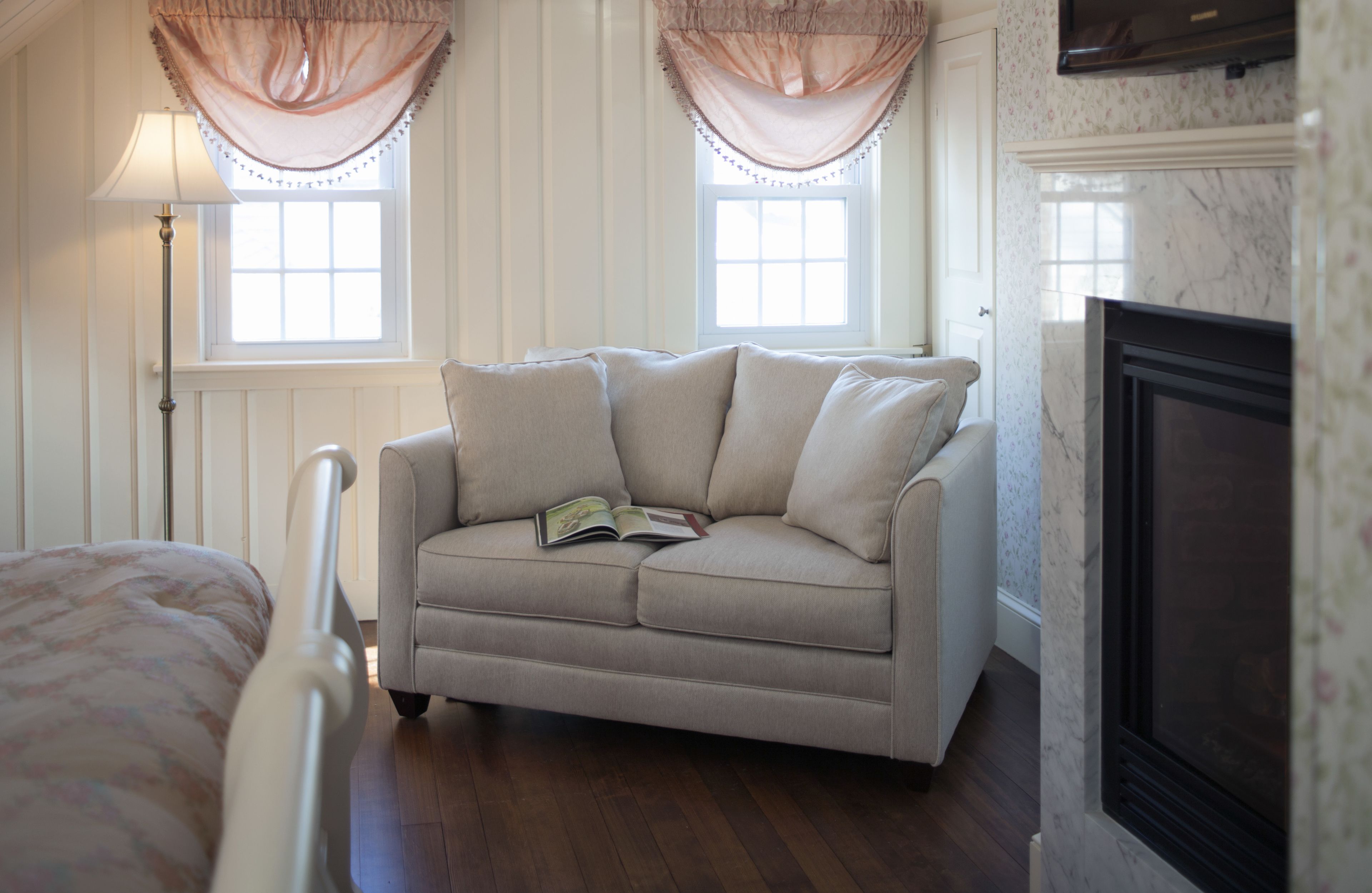 A room with a beige sofa, a fireplace, and a window with curtains.