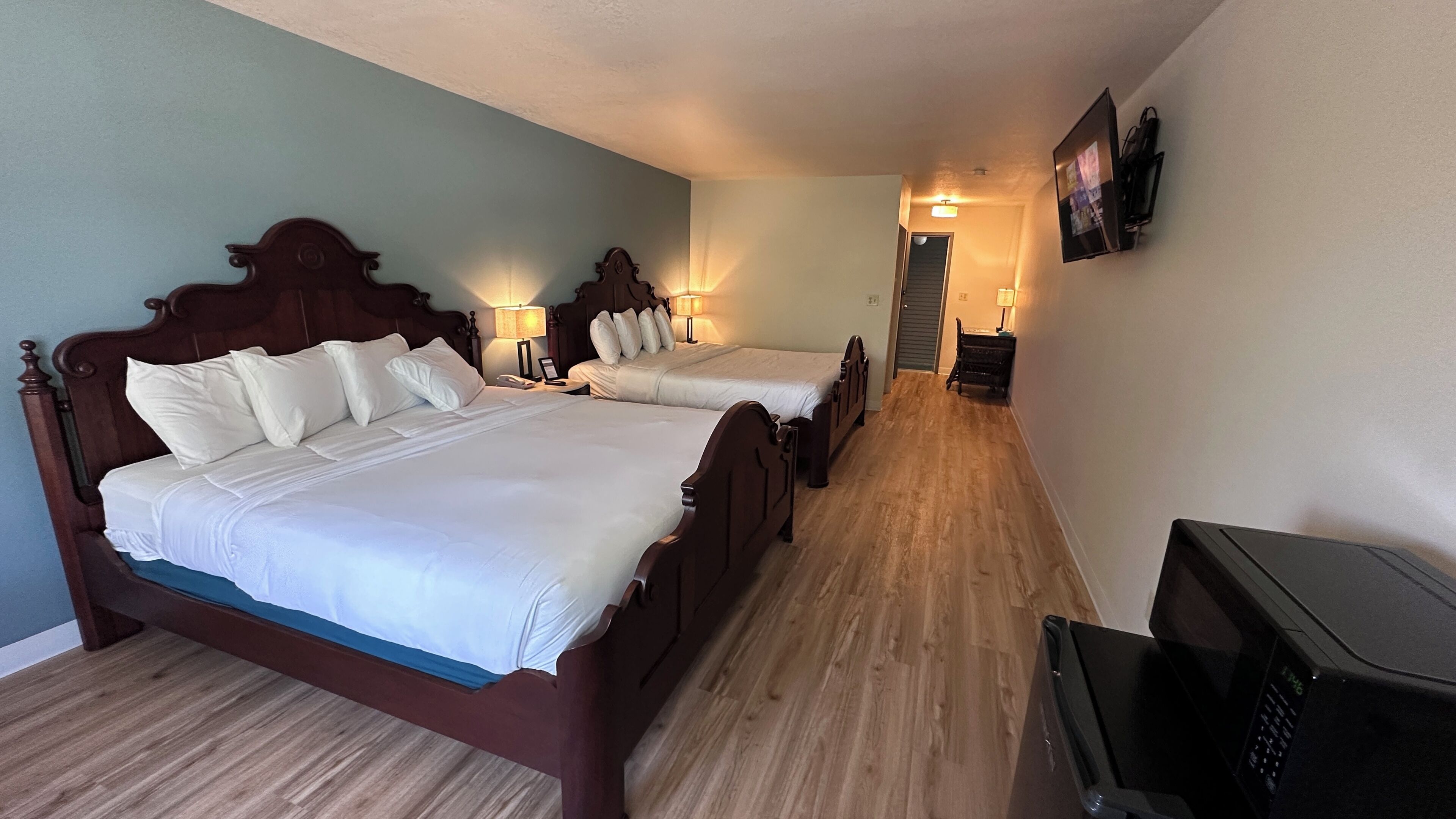 Una habitación de hotel con dos camas de madera, un televisor y un escritorio.