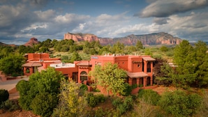 A red-roofed building with a sign reading "Las Posadas" surrounded by lush greenery and red rock formations in the background. - Las Posadas of Sedona (Sedona)