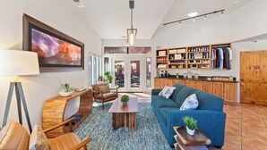 A spacious living area with a blue sofa, wooden coffee table, and a large TV screen. - Las Posadas of Sedona (Sedona)