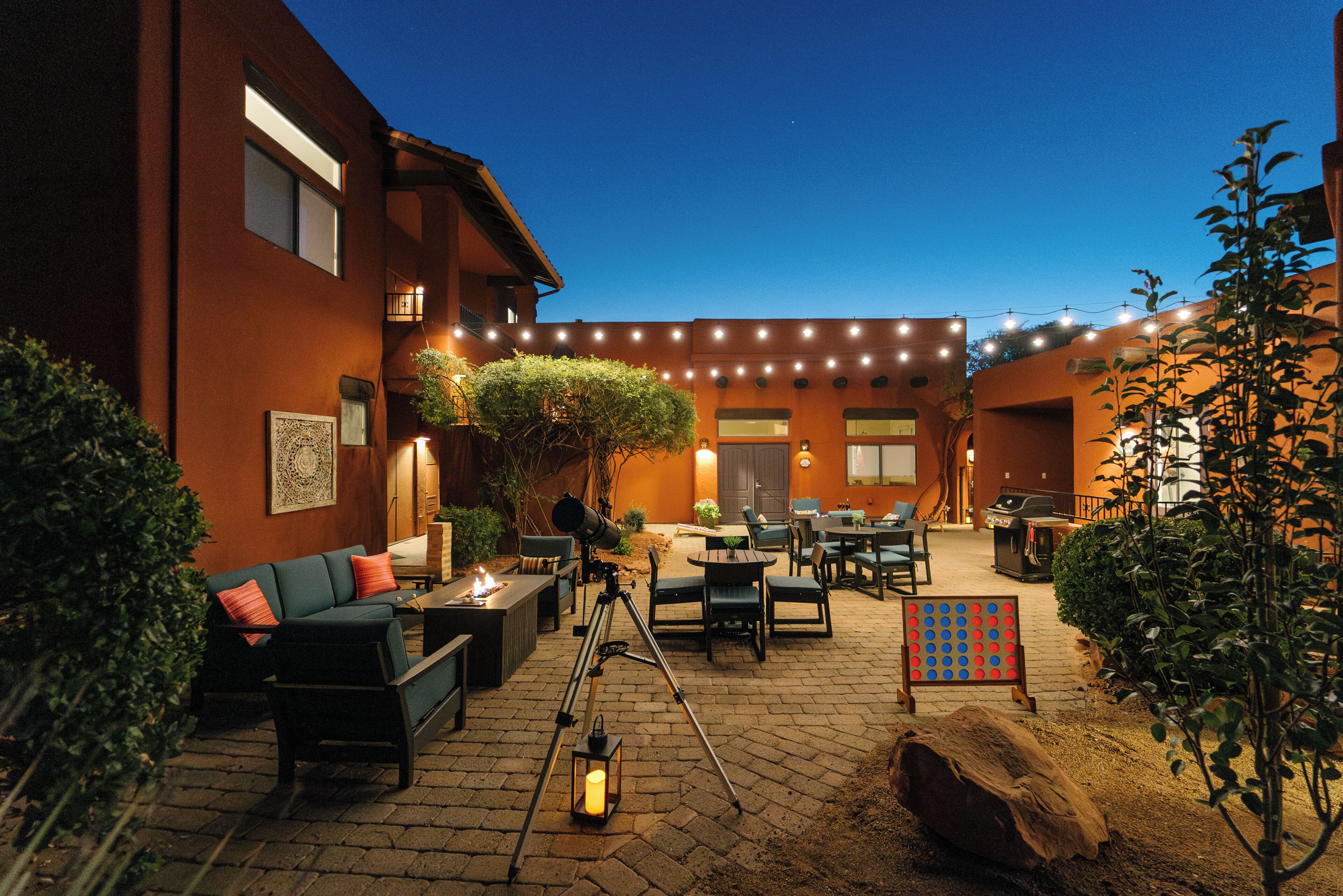 Un patio al aire libre con asientos, un telescopio y luces colgantes.