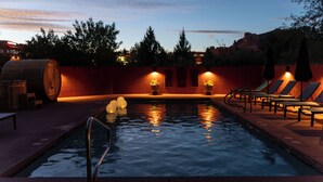 A swimming pool with lounge chairs and a wooden barrel, surrounded by a red wall and trees. - Las Posadas of Sedona (Sedona)