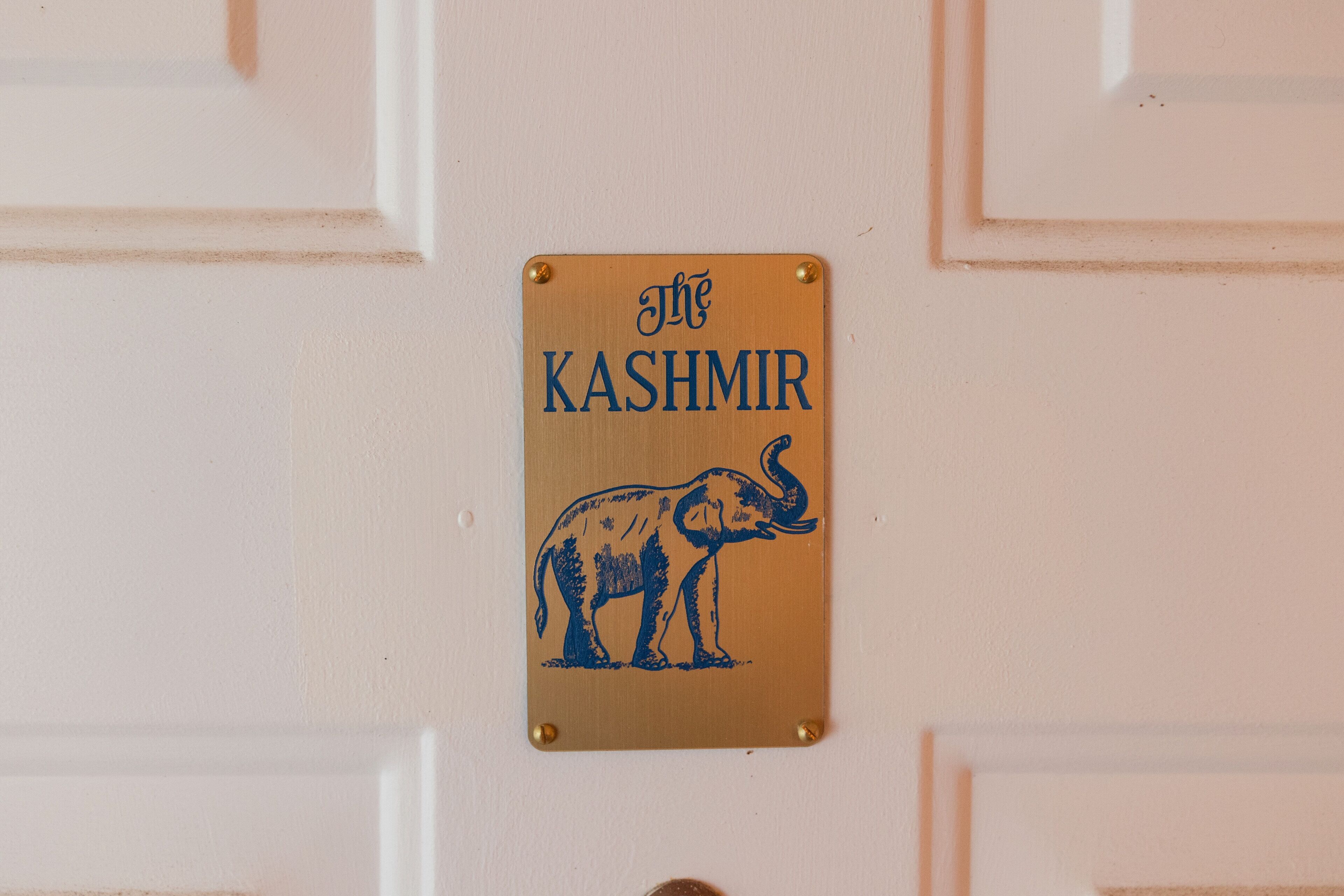 A sign with an elephant and the text 'The Kashmir' on a white door.