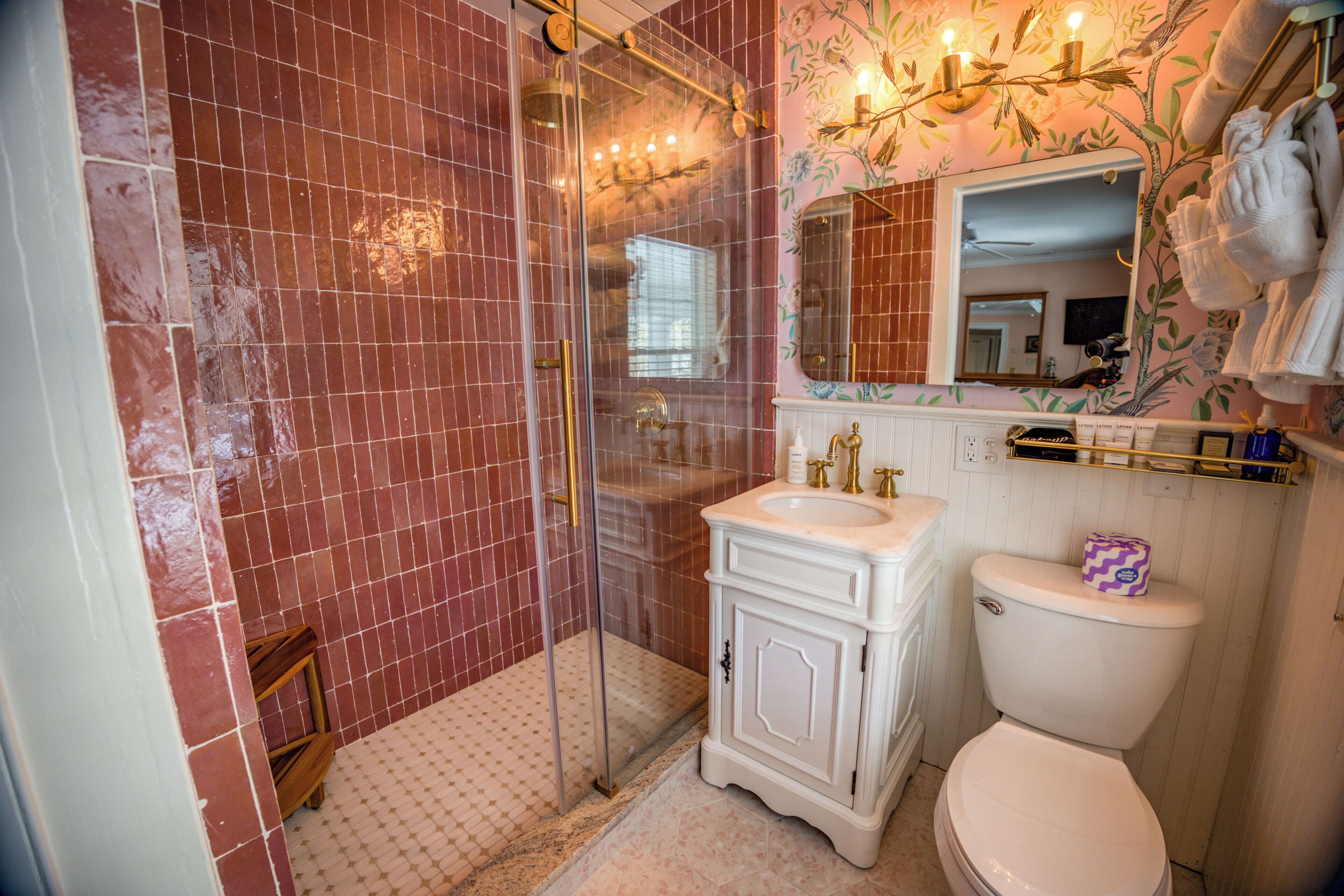 Un baño con cabina de ducha de vidrio, lavabo blanco y retrete.