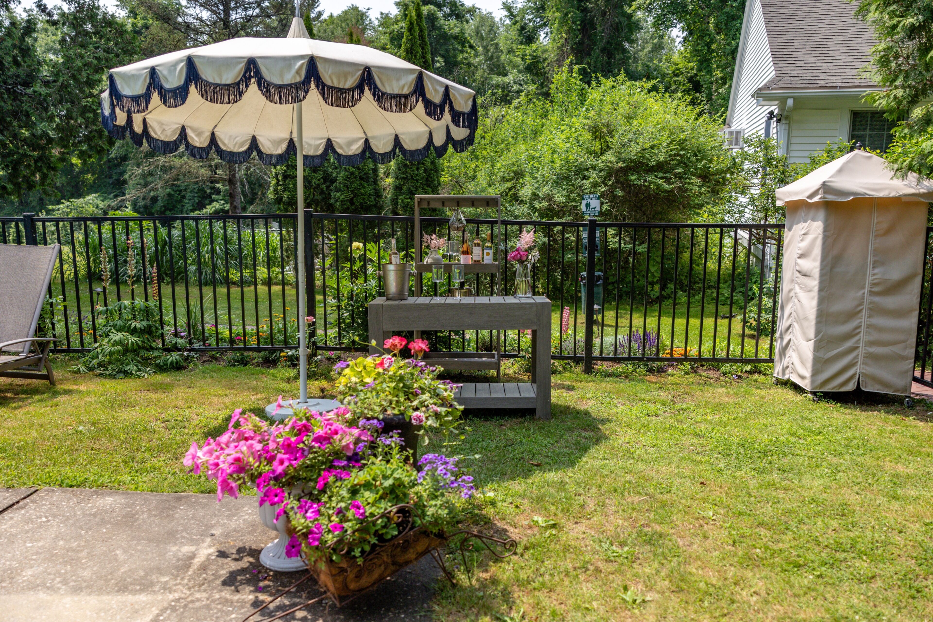 A patio with a table, a chair, a potted plant, and a tent.