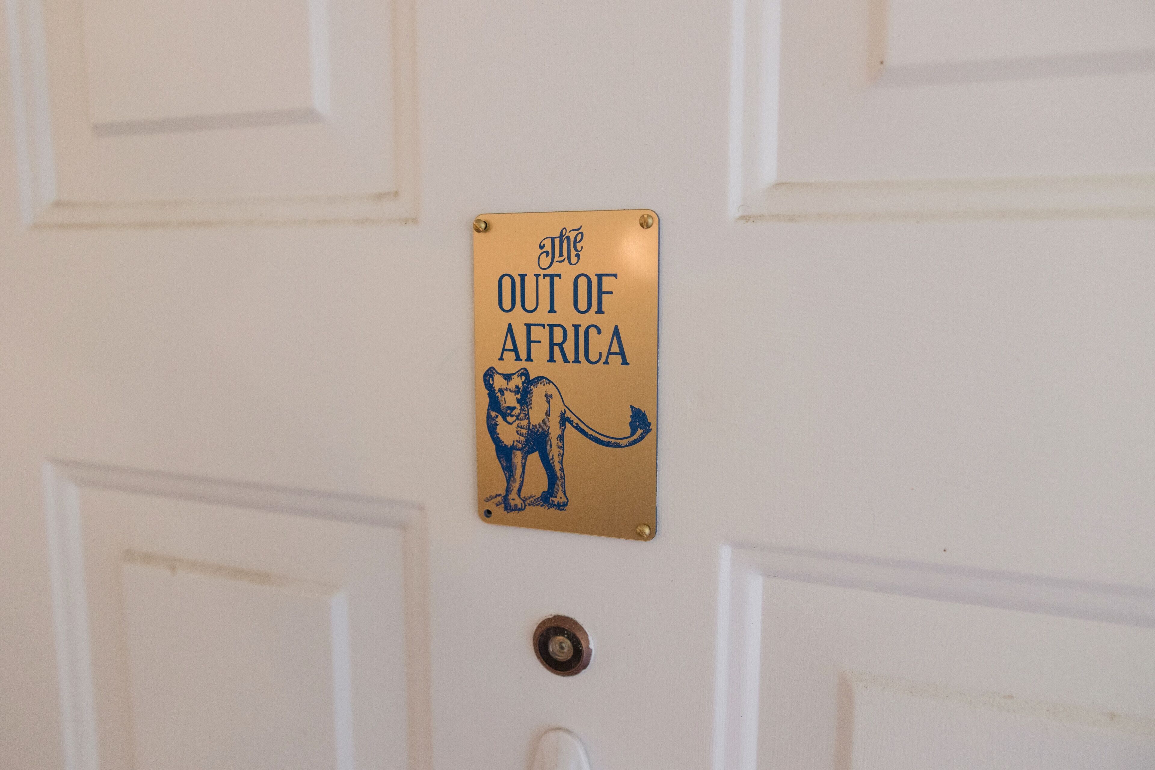 A sign on a door with the text 'The OUT OF AFRICA' and a lion illustration.