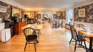 Une salle à manger spacieuse avec un plancher en bois, des chaises noires et une table centrale.