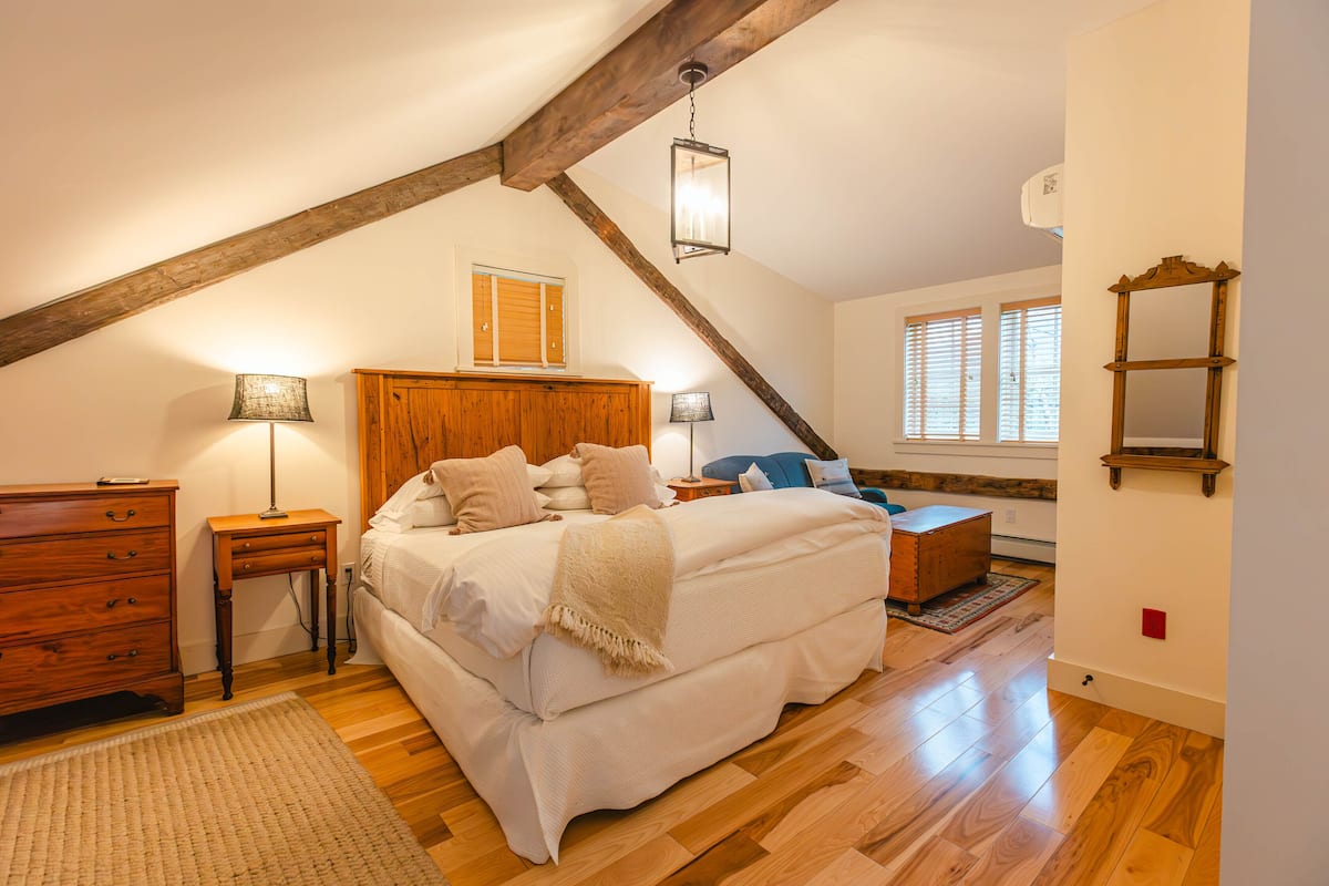 A bedroom with a wooden bed, bedside tables, a dresser, and a mirror on the wall.