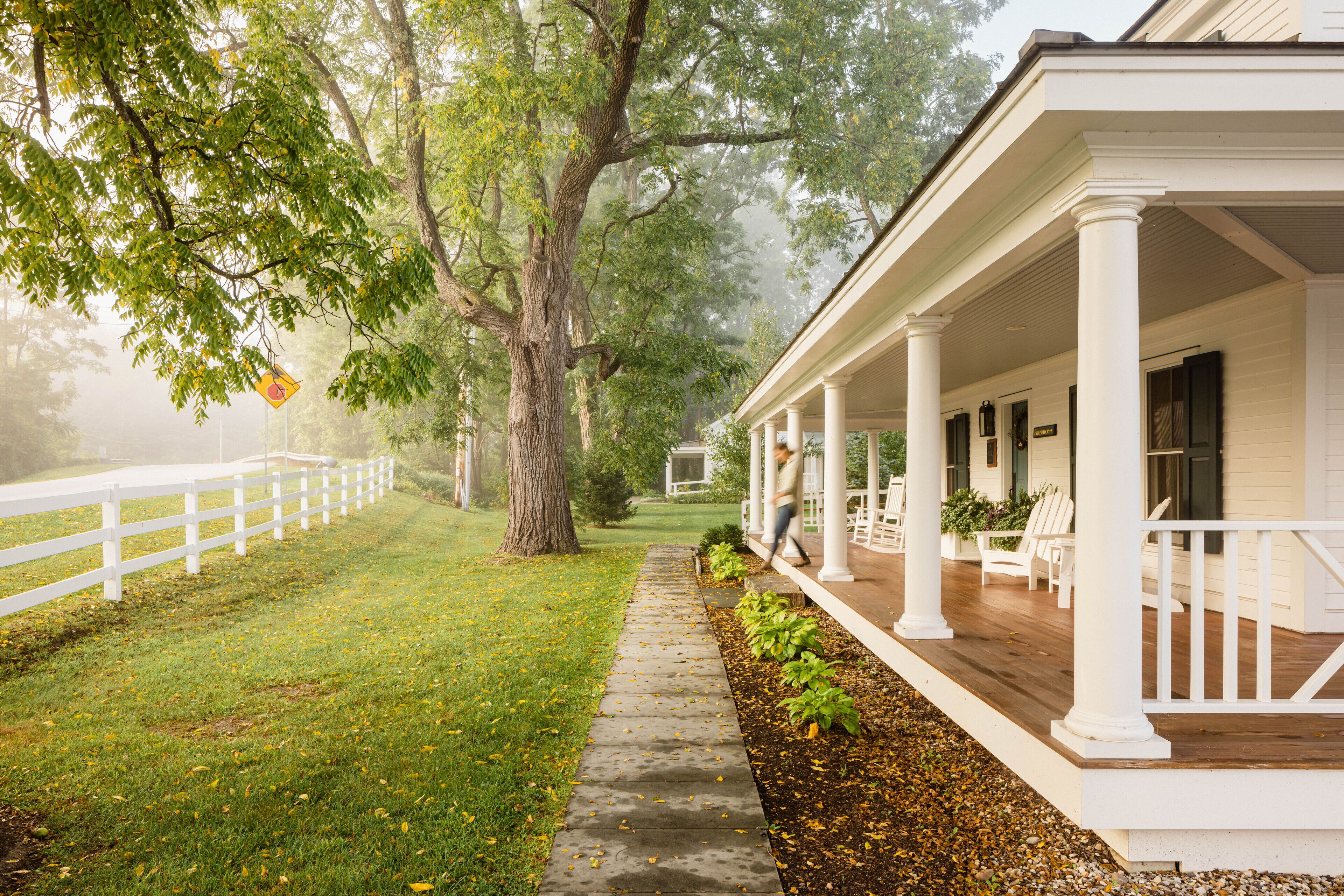 A covered porch with white columns and a white fence.