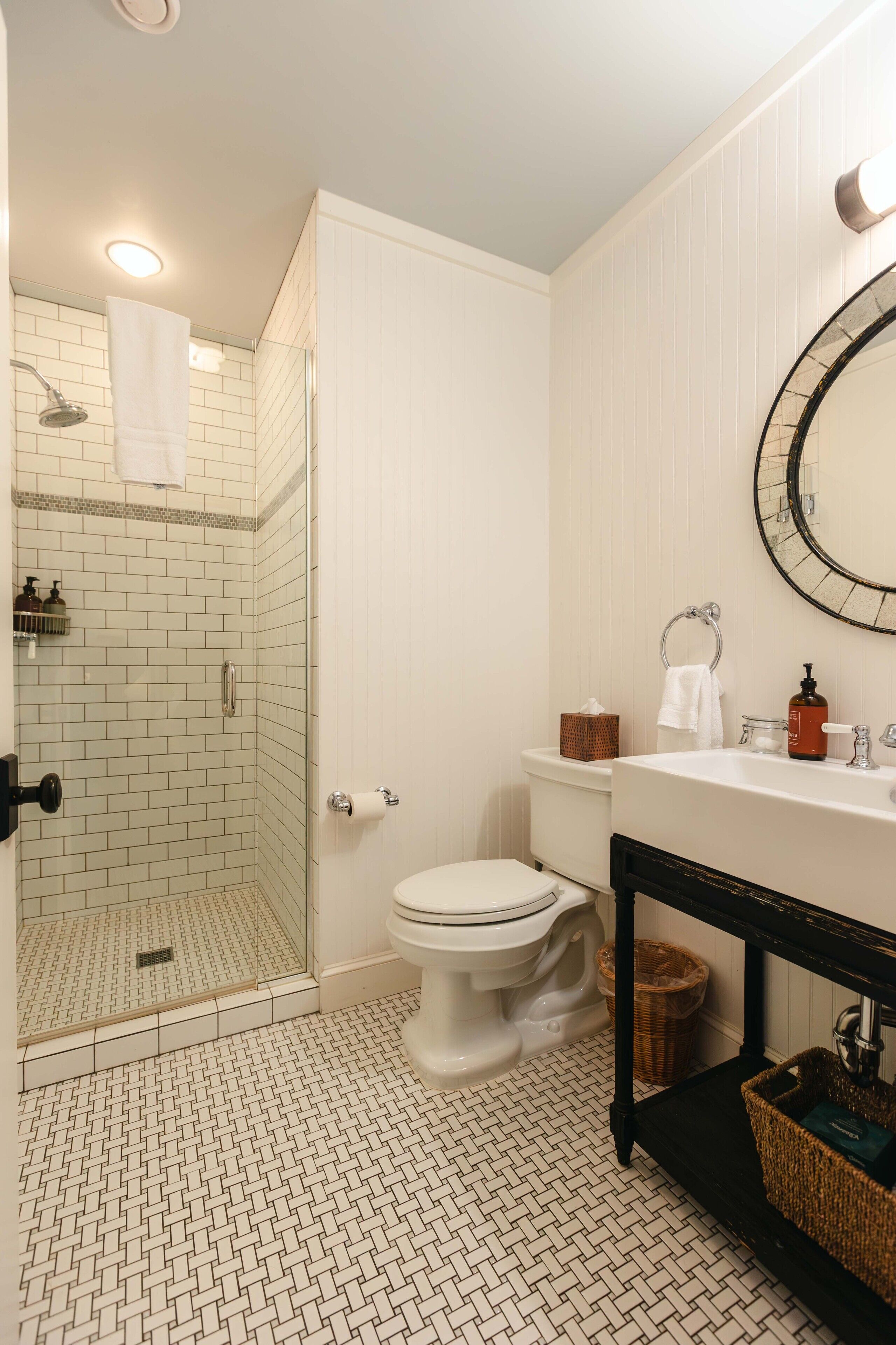 Baño con ducha de vidrio, inodoro, lavabo y espejo.