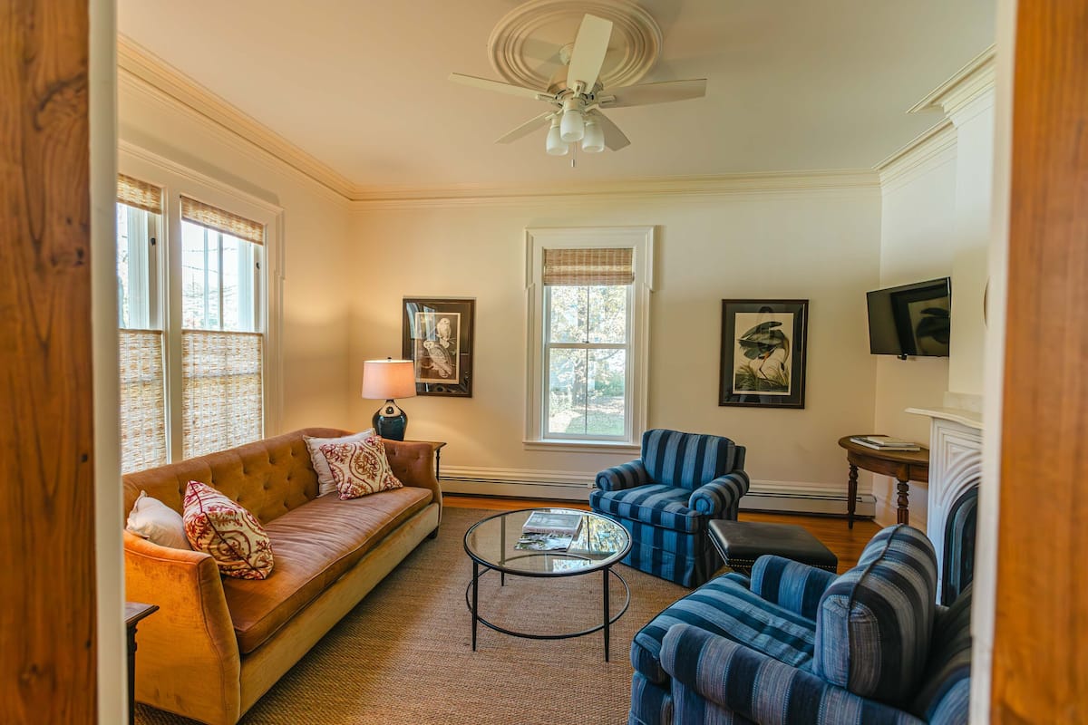 A living room with a sofa, armchairs, a coffee table, and a fireplace.