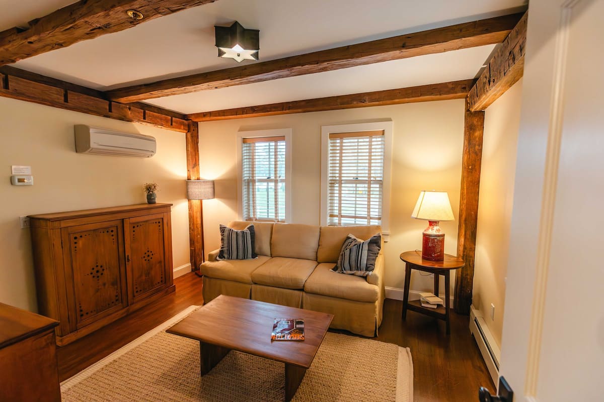 A cozy living room with a wooden ceiling, a sofa, a coffee table, and a lamp.