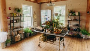 A rustic room with wooden floors, a metal cart, shelves with plants, and a refrigerator. - Hill Farm Inn (Arlington)
