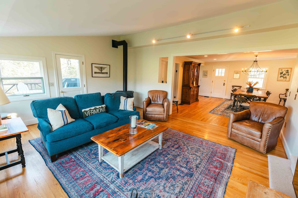 A spacious living room with a blue sofa, a wooden coffee table, and a patterned rug.