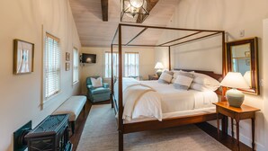 A four-poster bed with a wooden frame, a bench, a small table with a lamp, and a mirror on the wall. - Hill Farm Inn (Arlington)