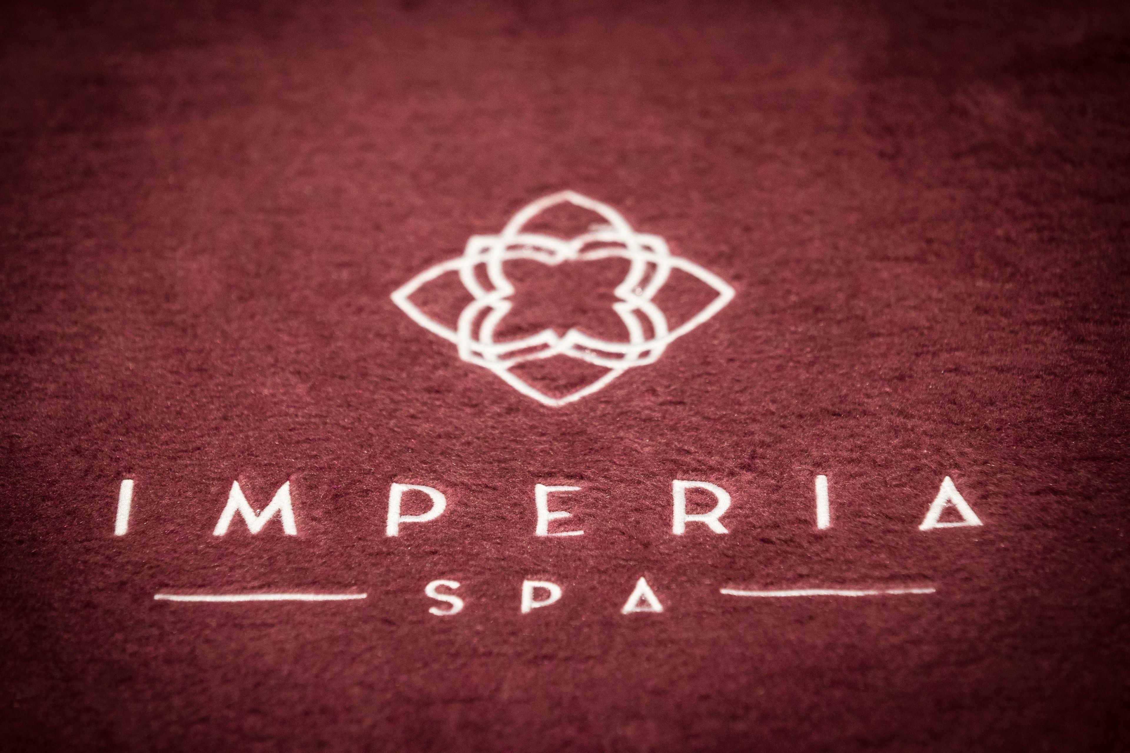 A logo with the text "IMPERIA SPA" on a textured surface.