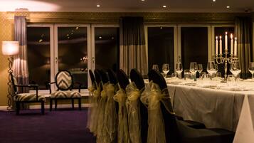 A dining area with a table set for a meal, chairs with ties, and a candelabra with candles.
