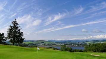 Enjoy a serene tee-off experience amidst rolling hills and a tranquil body of water.