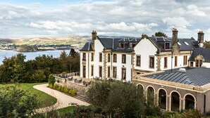 A large, historic building with multiple chimneys, large windows, and a well-maintained garden.
