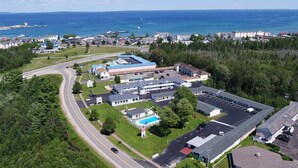 An aerial view of a coastal town with a large building complex, a parking lot, and a road curving through the area. - Starlite Budget Inn (Mackinaw City)