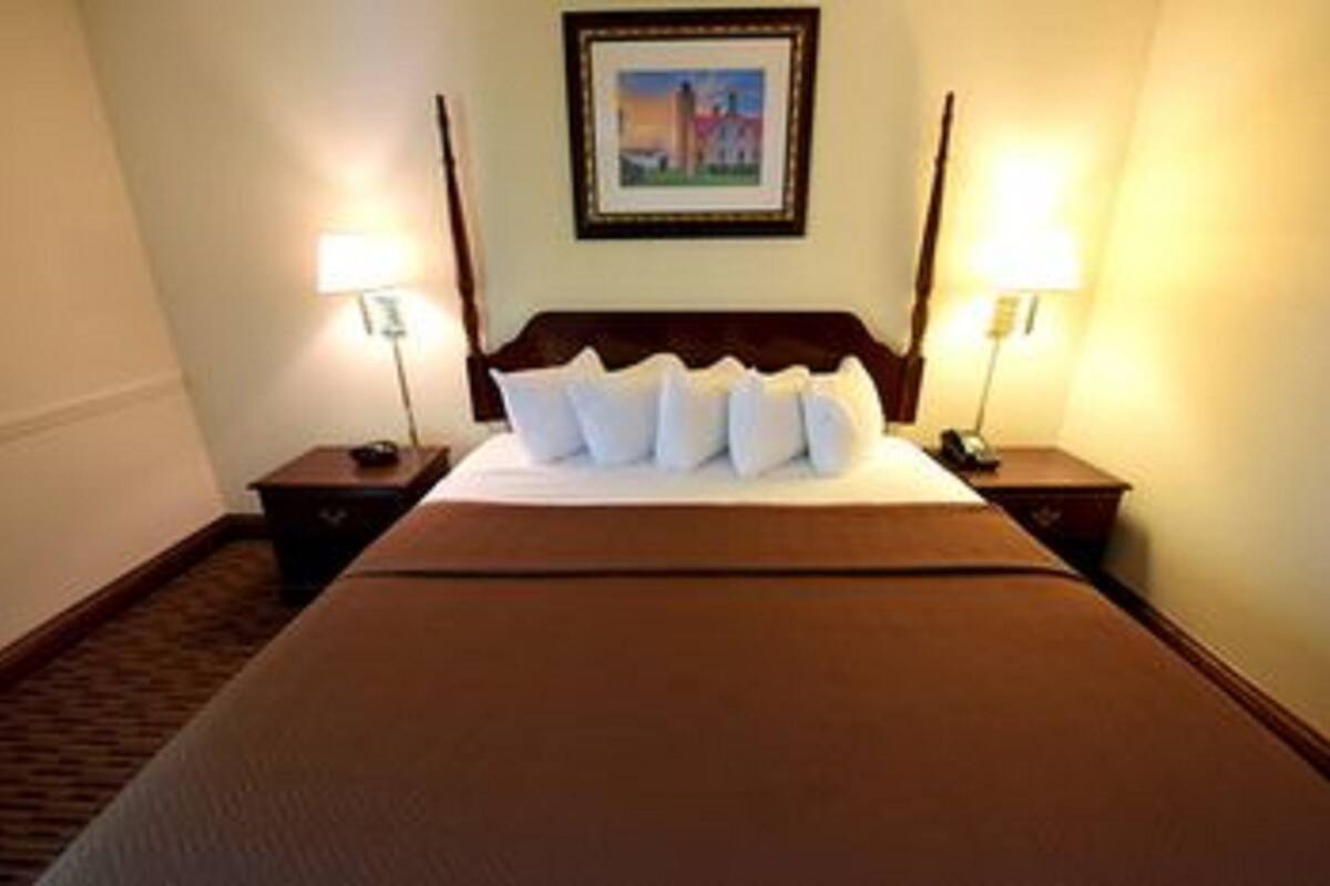 A hotel room with a large bed, two bedside tables with lamps, and a framed picture on the wall.