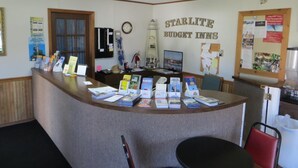 A reception desk at Starlite Budget Inns with informational brochures, a clock, and a bulletin board. - Starlite Budget Inn (Mackinaw City)