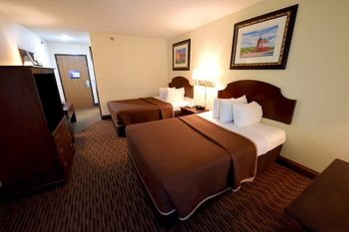 A hotel room with two single beds, a desk, a chair, and a wardrobe.