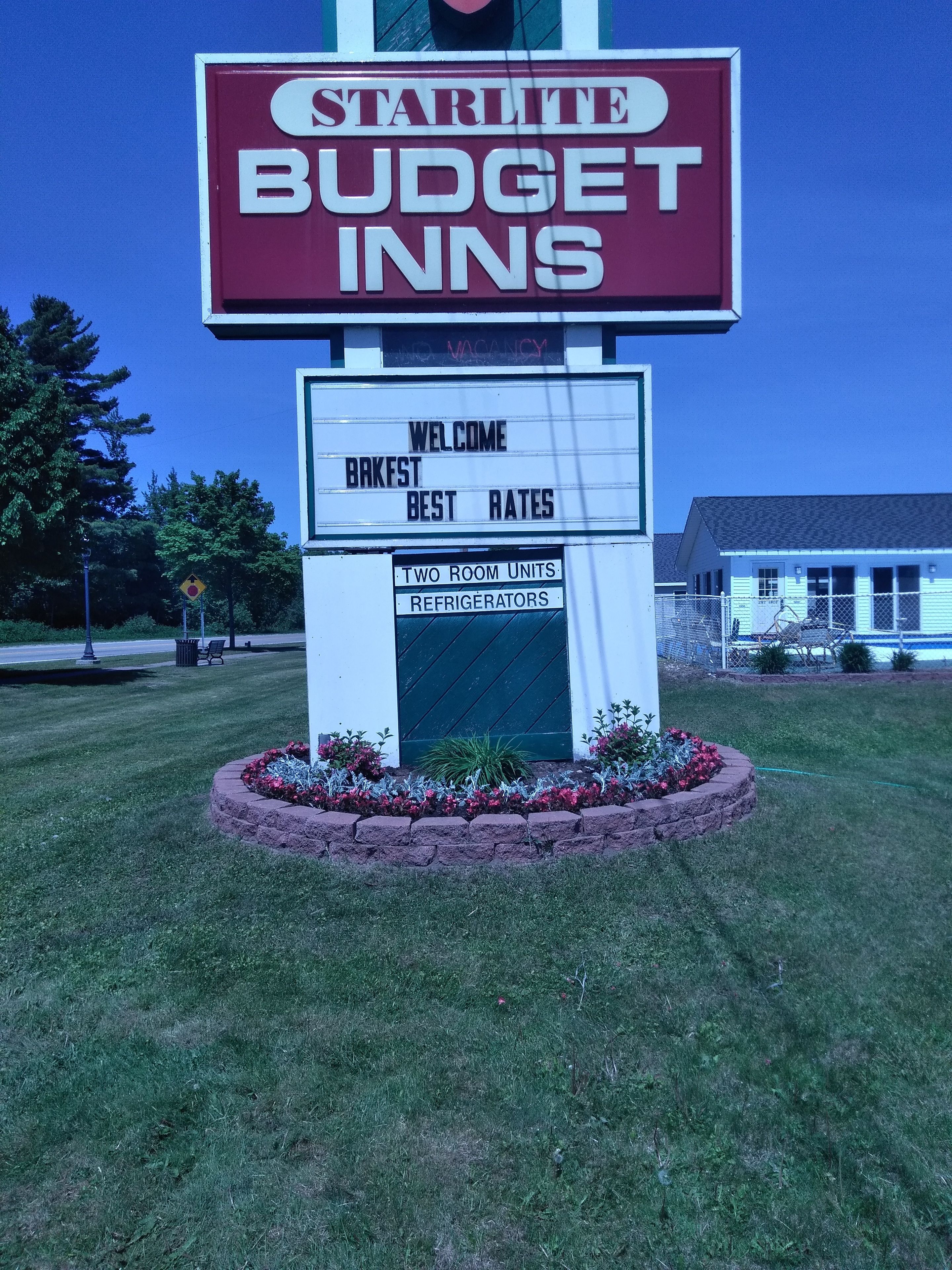 Letrero de StarLite Budget Inns que anuncia: 'Bienvenidos, Desayuno, Las Mejores Tarifas' y 'Apartamentos con Dos Habitaciones, Refrigeradores'.