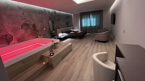 A modern bedroom with a large bed, a sitting area, a vanity, and a bathroom. - Pegasus Hotel (Sassari)