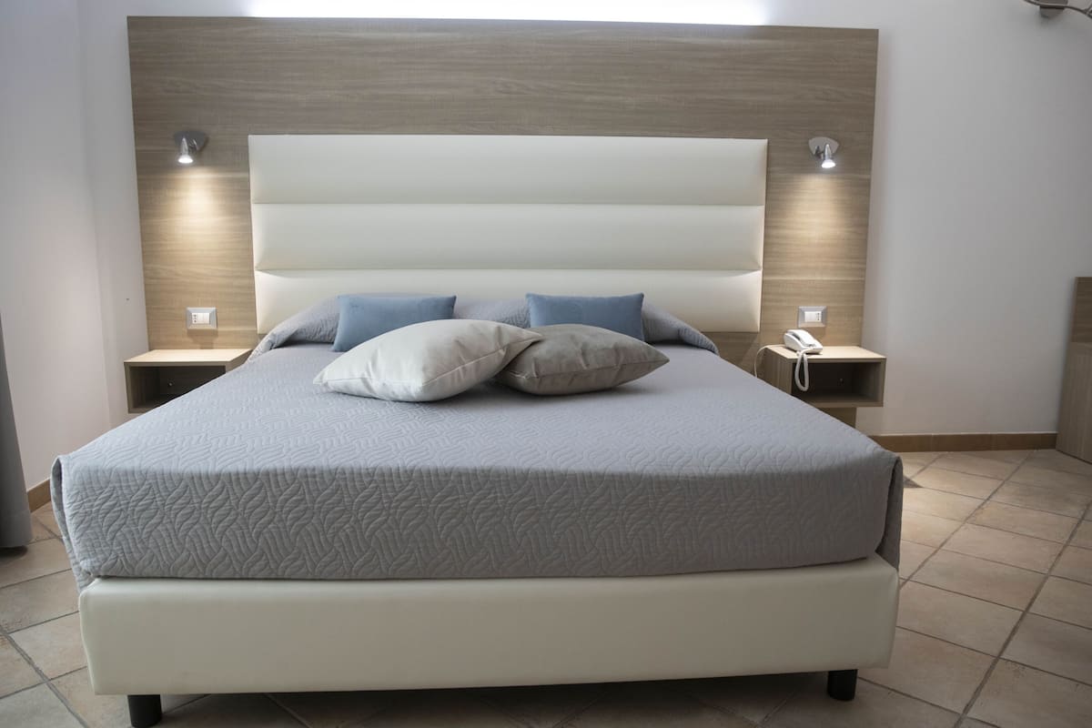 A modern bedroom with a large bed, two bedside tables, and a headboard.