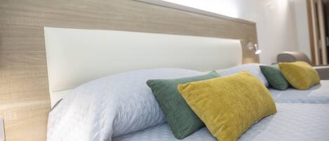 A bed with a wooden headboard and multiple pillows in different colors.