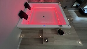 A modern spa with a heated floor, a large rectangular tub, and a decorative wall. - Pegasus Hotel (Sassari)