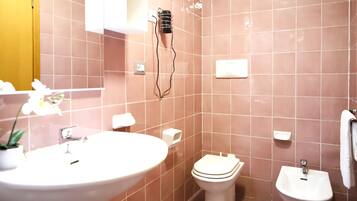Un baño con lavamanos, inodoro, bidé y un perchero para toallas.