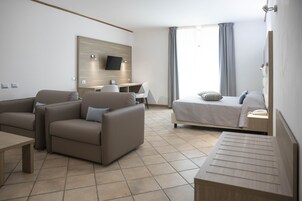 Una habitación de hotel moderna con una cama, un escritorio, un sofá y un televisor montado en la pared.