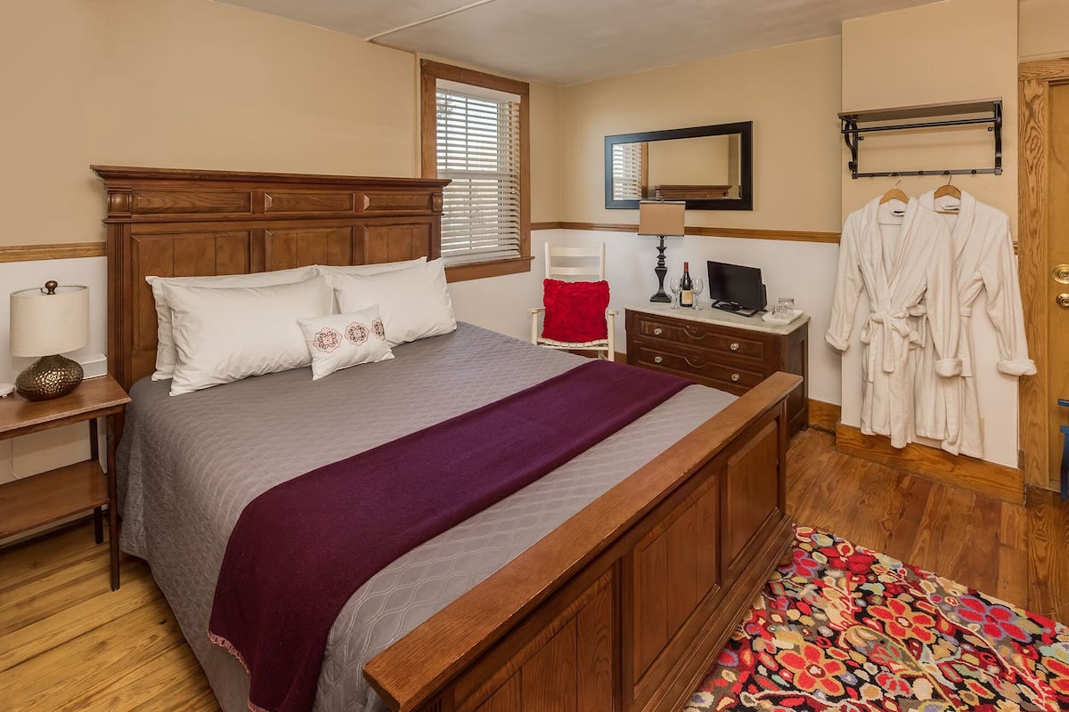 A neatly arranged bedroom with a bed, bedside table, dresser, and a mirror.