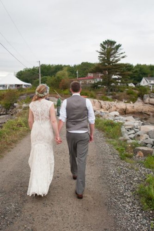 A couple walking on a gravel path surrounded by greenery and rocks. - The Craignair Inn & Restaurant (Spruce Head)