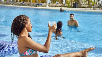 Ein Pool mit entspannten Personen, wolkenlosem Himmel und einer gefliesten Kante.