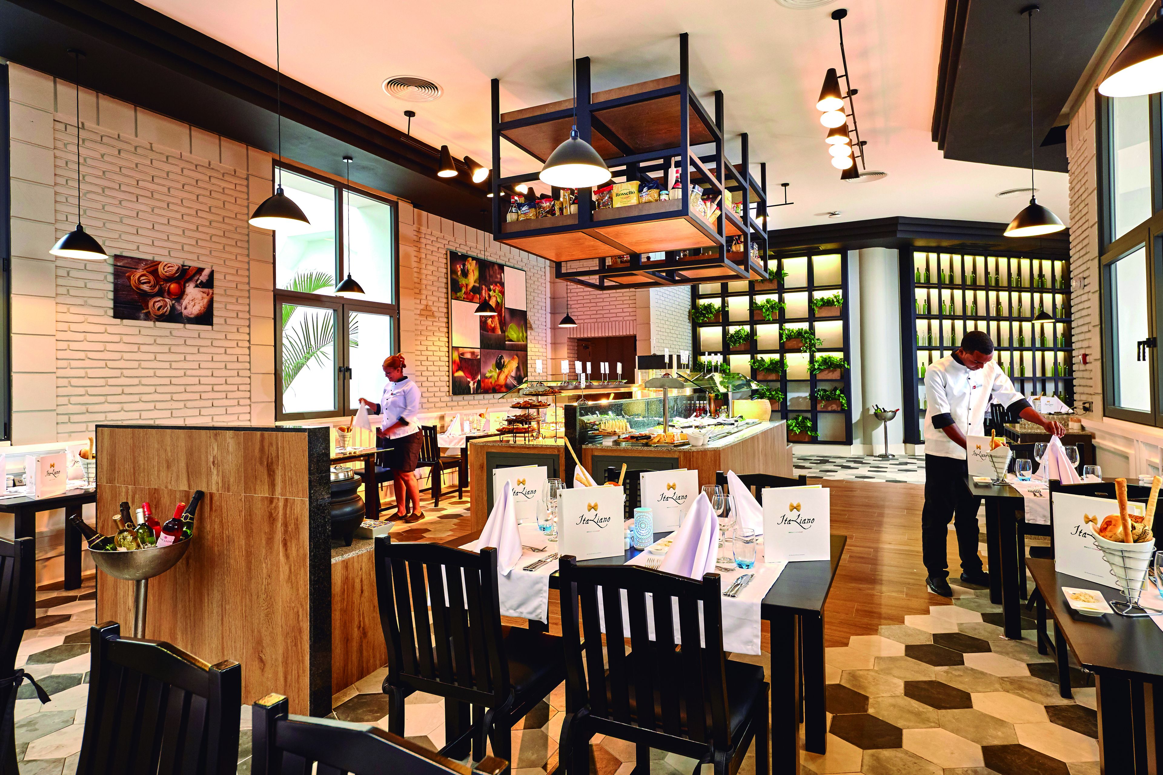 A restaurant with a brick wall, wooden tables, and hanging lights.