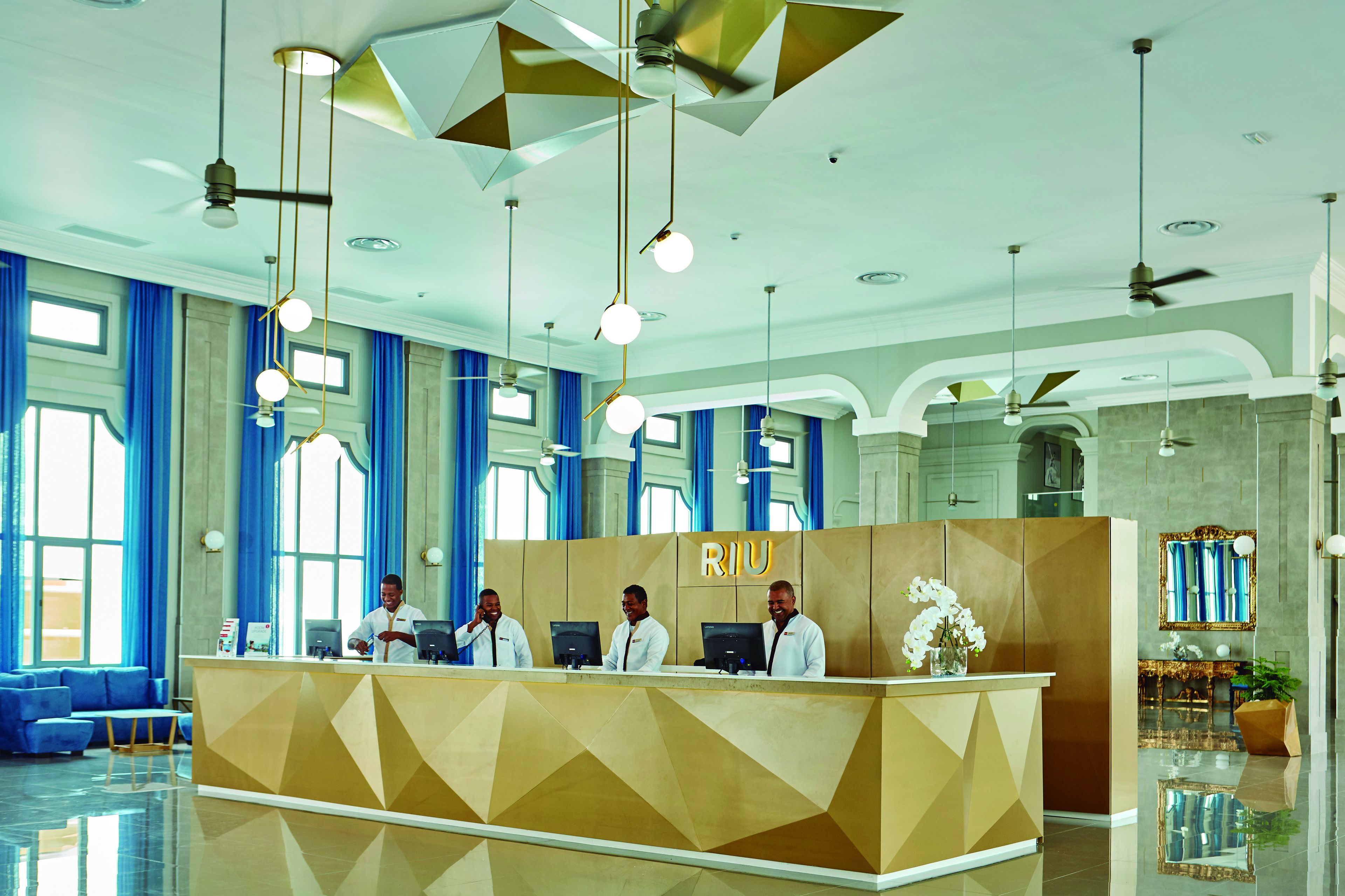 A reception area with a geometric design, a reception desk, and three staff members.