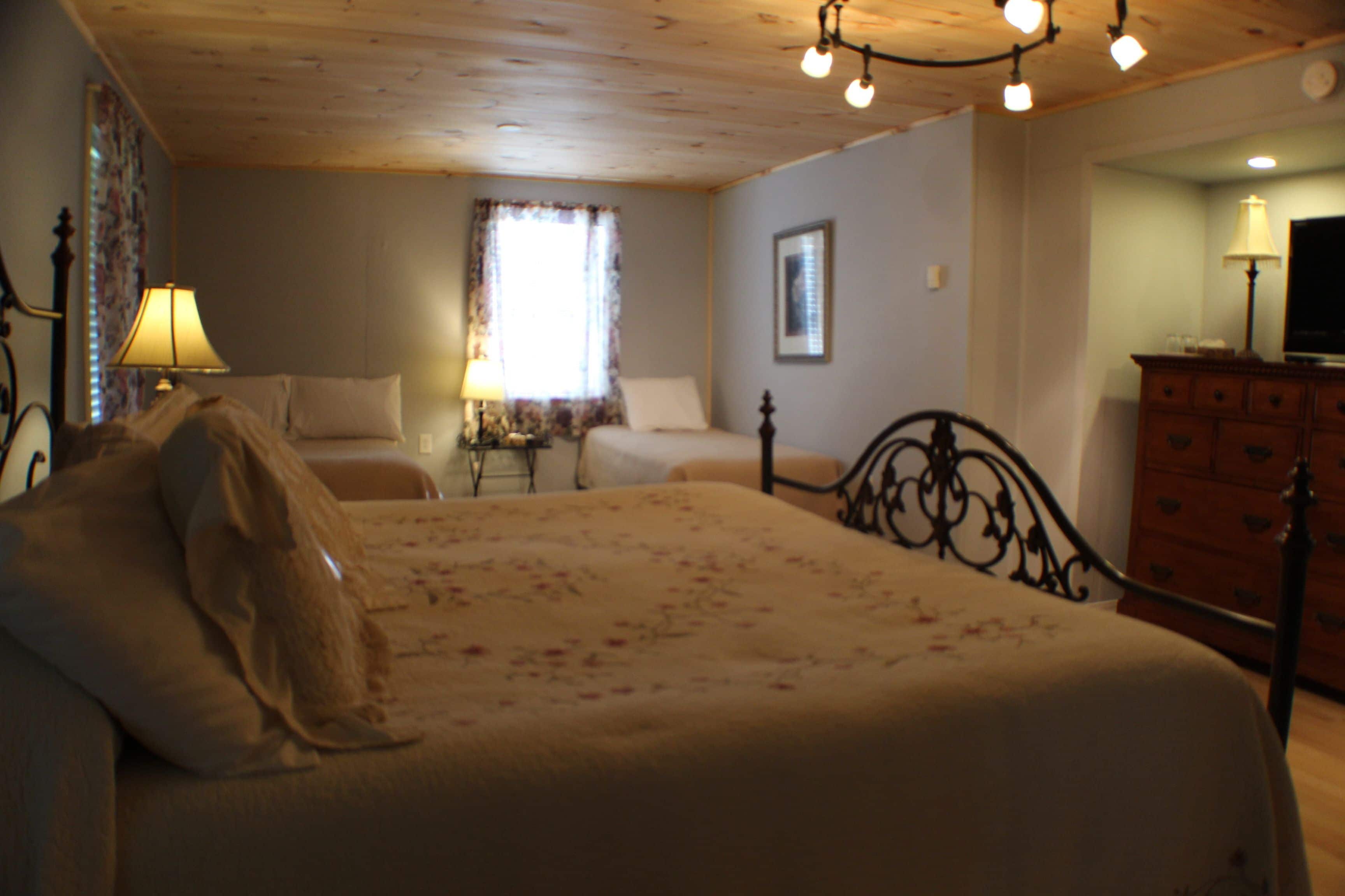A bedroom with a bed, a dresser, a lamp, and a television.
